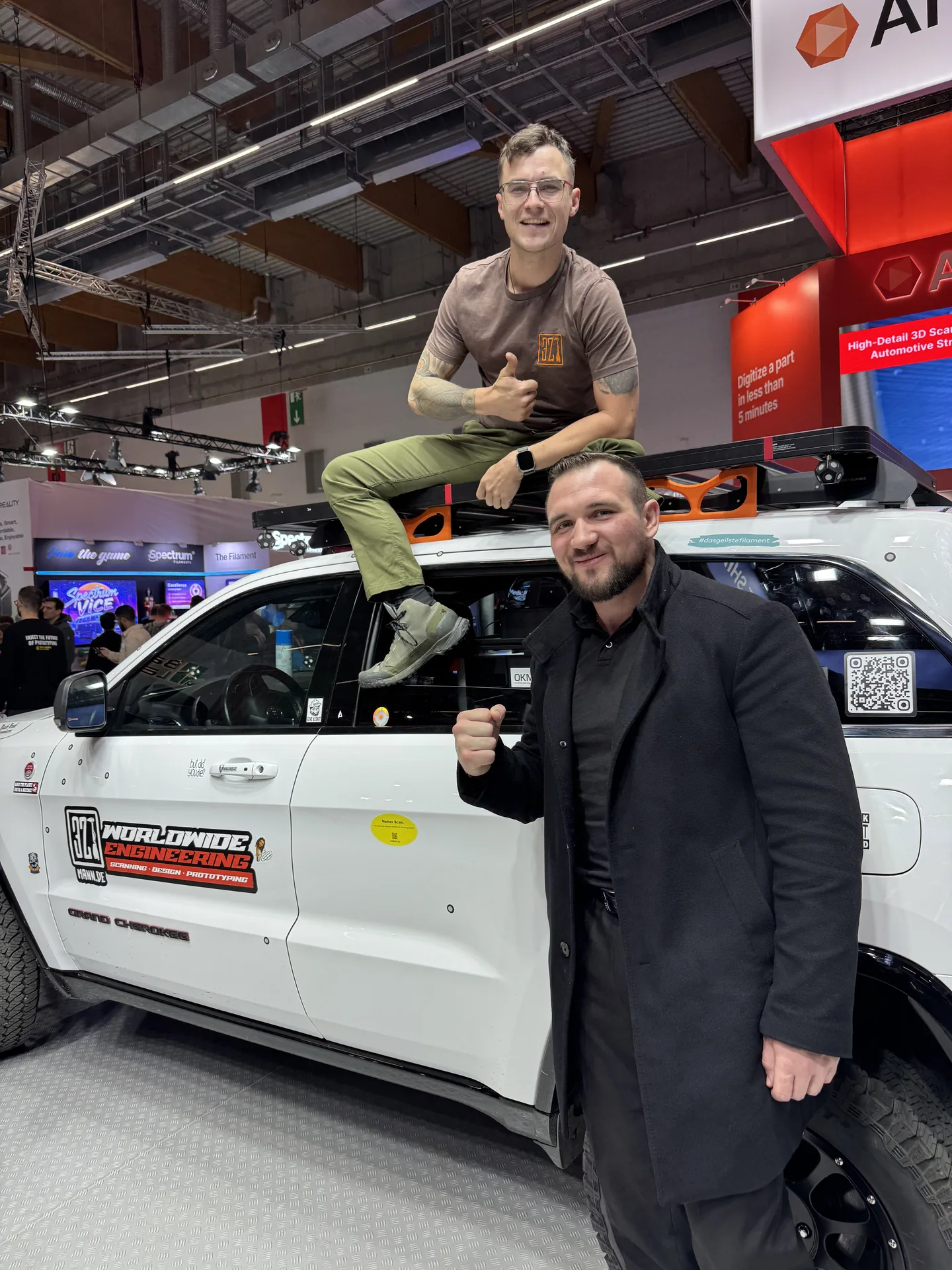 Zwei Personen am Jeep-Messefahrzeug auf einer Fachmesse.
