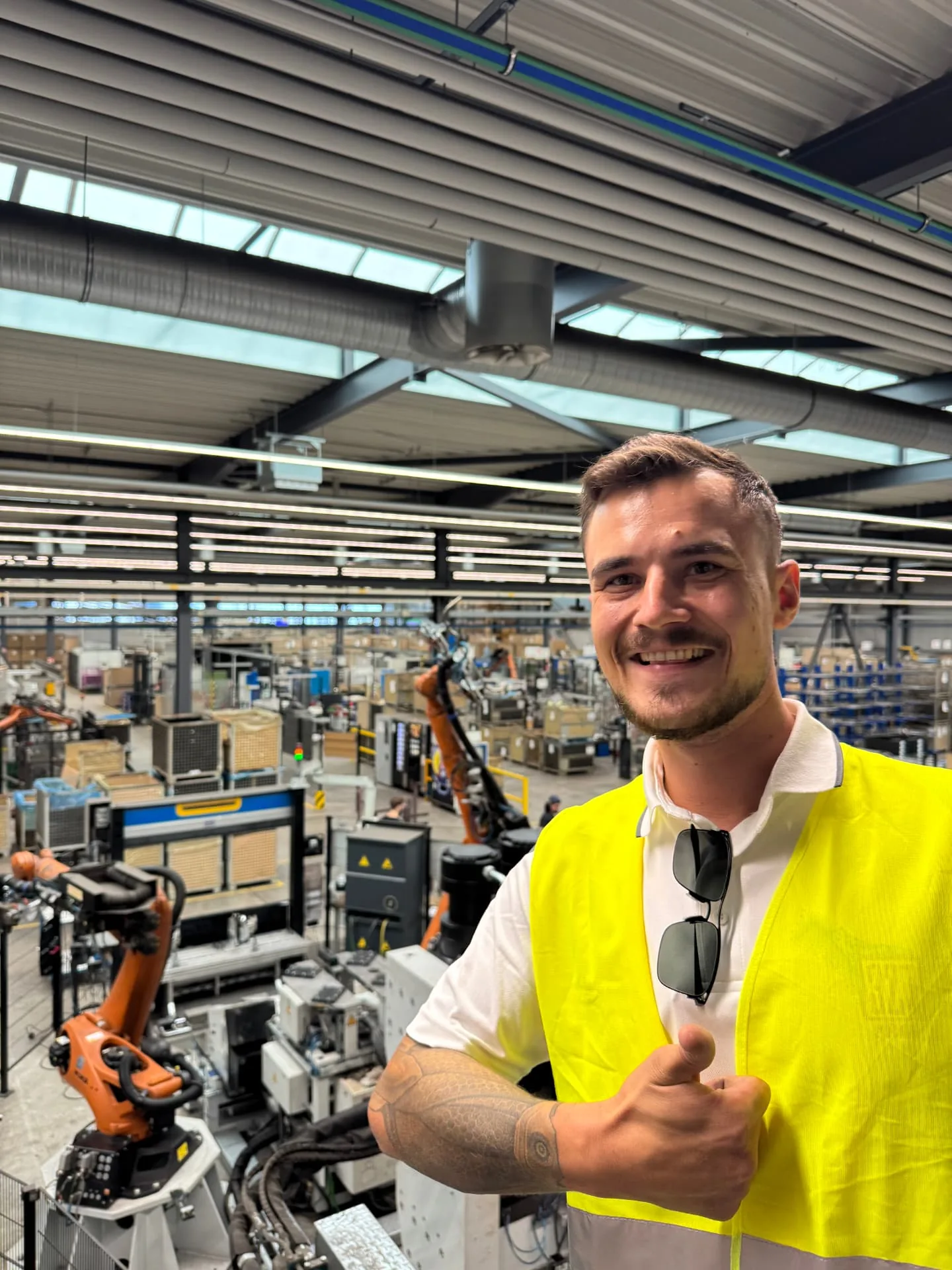 Kundenbesuch Automobilbranche: Person in Warnweste in einer Fabrikhalle.