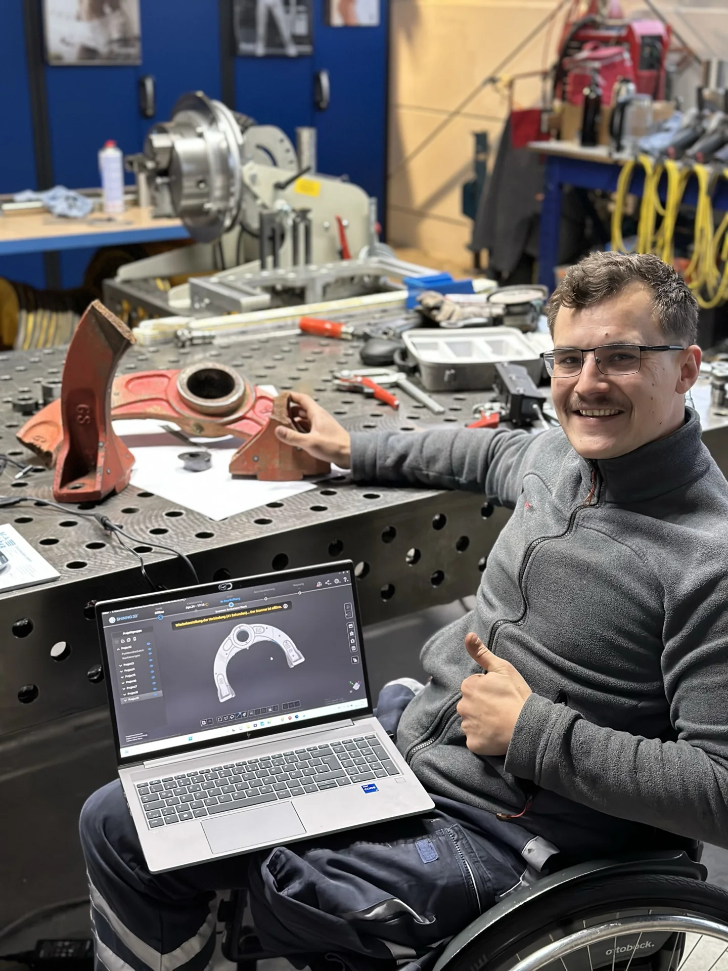 Lukas Heizmann mit zerbrochener Lagerbrücke am Arbeitstisch und Laptop.